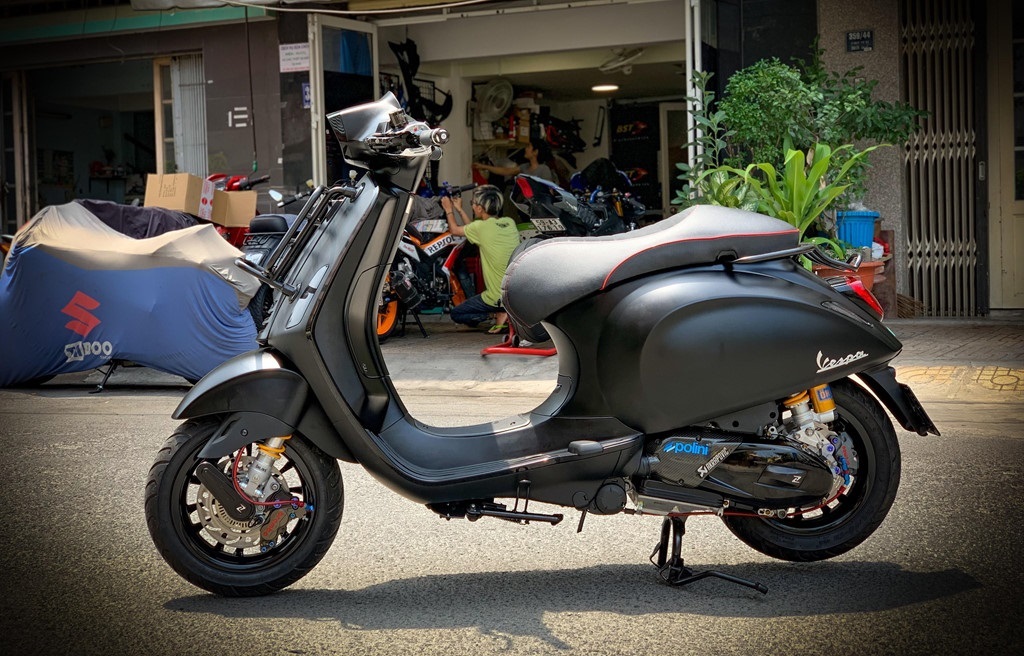 Chiếc Vespa độ màu xanh ngọc với yên xe da nâu, mang phong cách cổ điển đầy lôi cuốn.